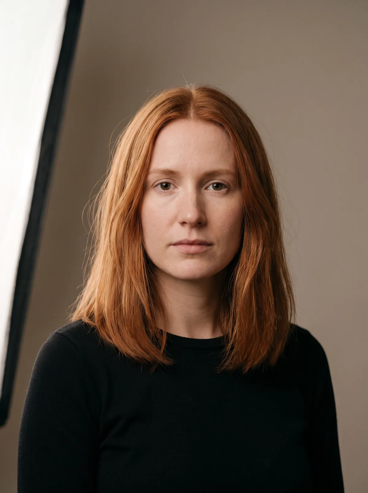 Frau mit kupferfarbenem, schulterlangem Haar, von vorn im Studio fotografiert.