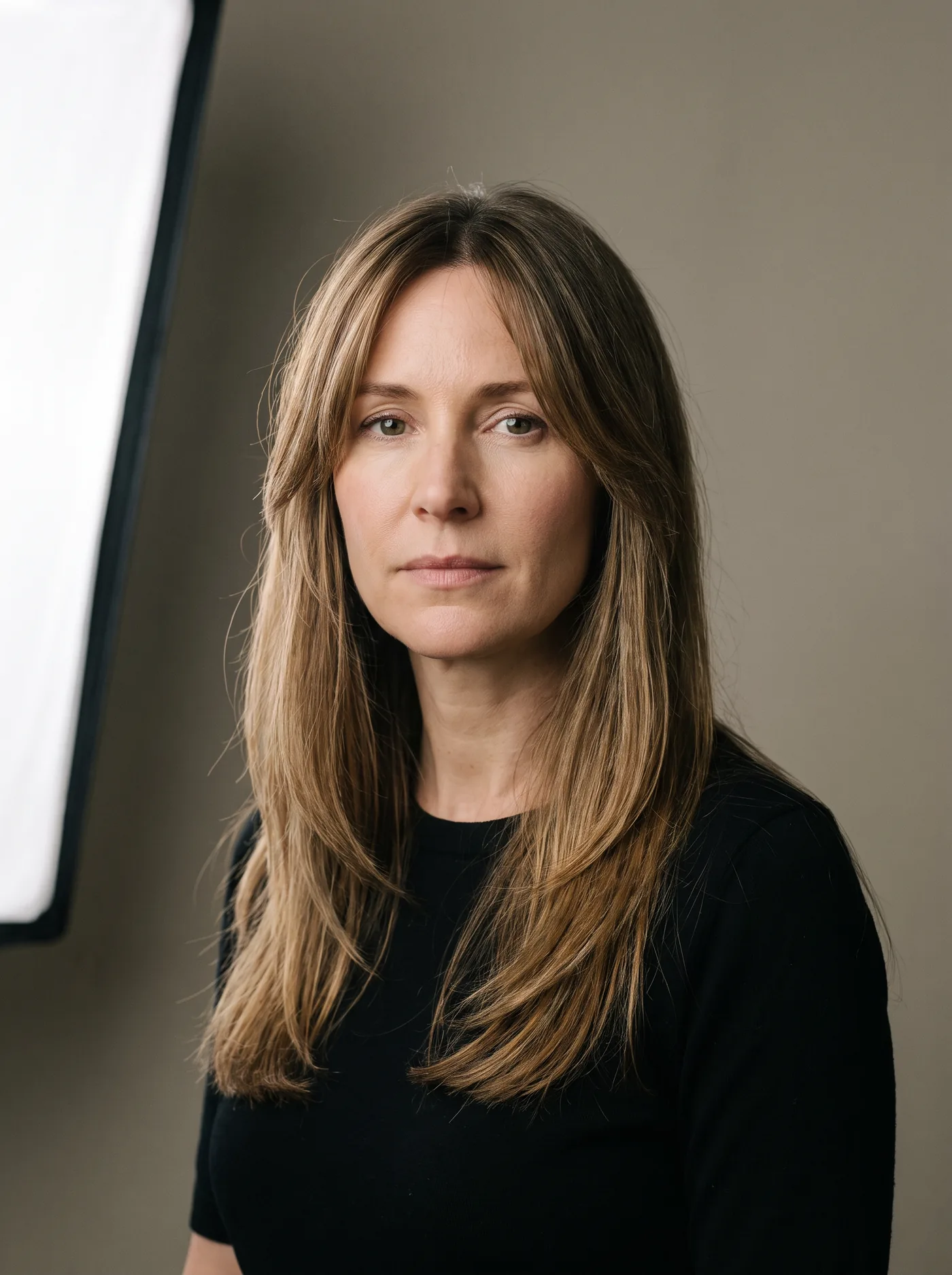 Frau mit langem, gestuftem Haar, von vorn im Studio fotografiert.