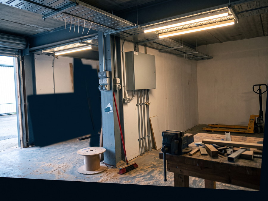 Fertige Elektroinstallation einer Werkstatt: Kabeltrassen unter der Decke, Steckdosen an der Stahlst&uuml;tze, zwei LED-B&auml;nder
