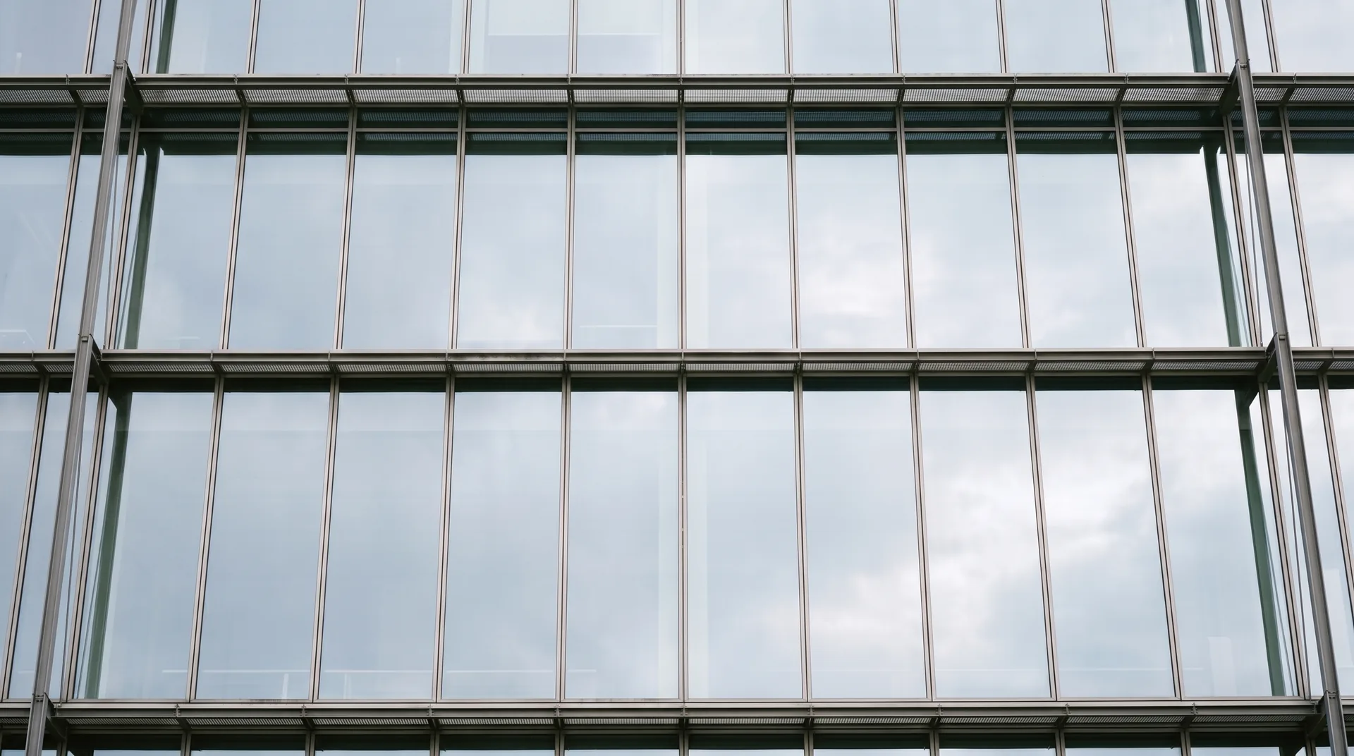 Dieselbe Fassade vollständig gereinigt, die Verglasung spiegelt den Morgenhimmel.