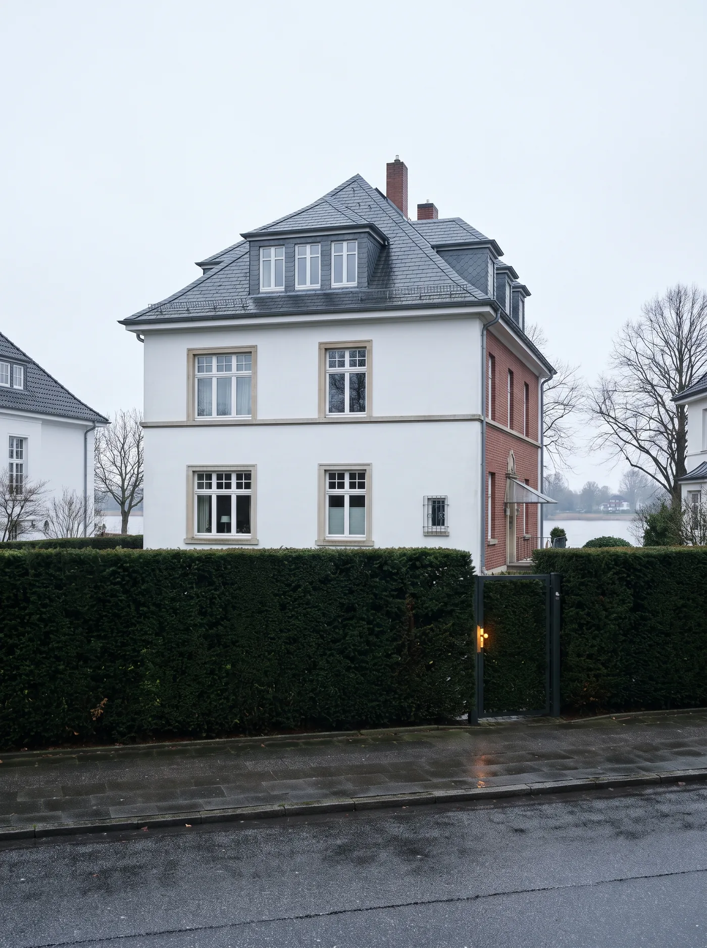 Weiße Villa an der Elbchaussee hinter altem Baumbestand.